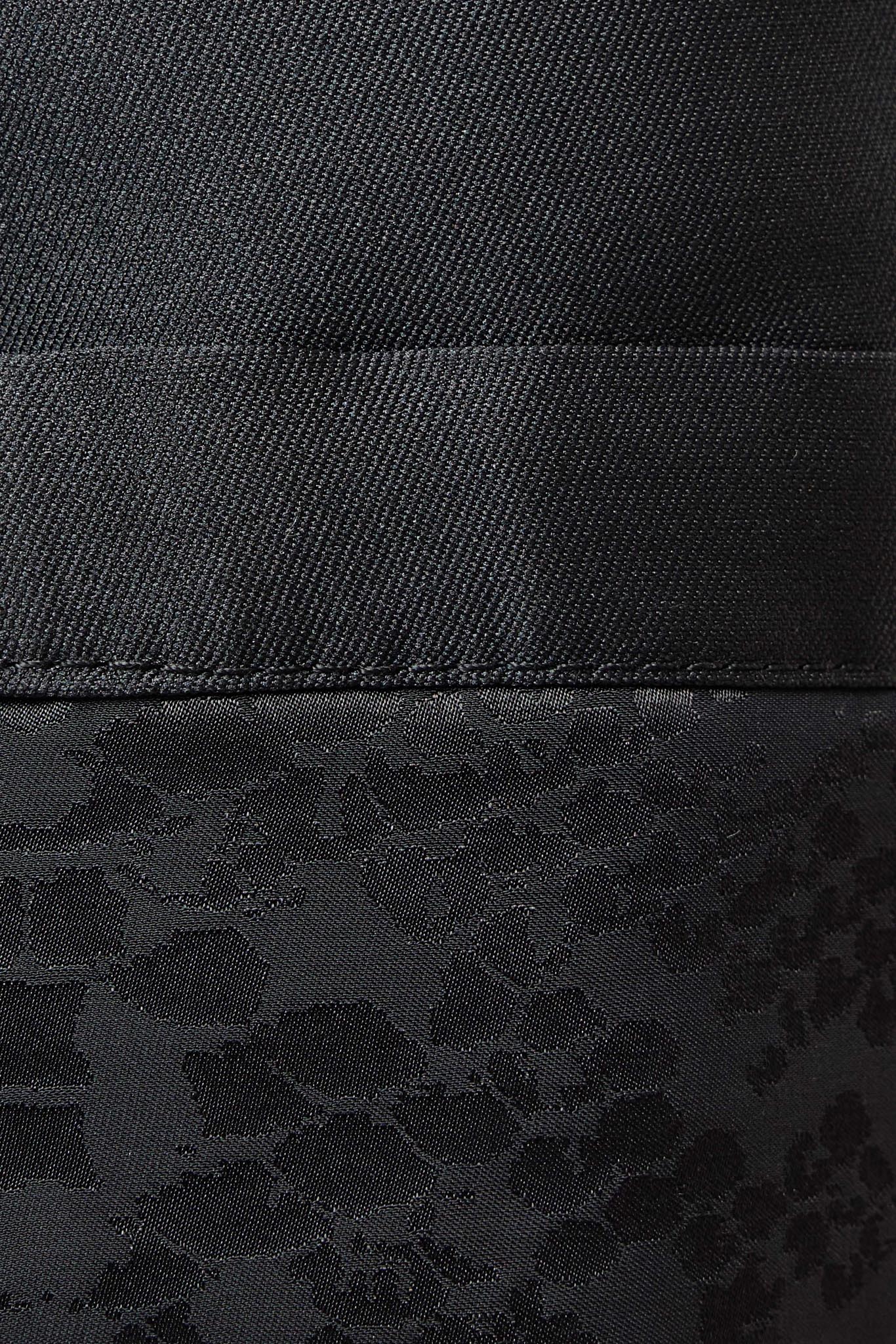 Close-up of a black textured fabric with a horizontal seam and a subtle tonal floral jacquard pattern in the lower section.