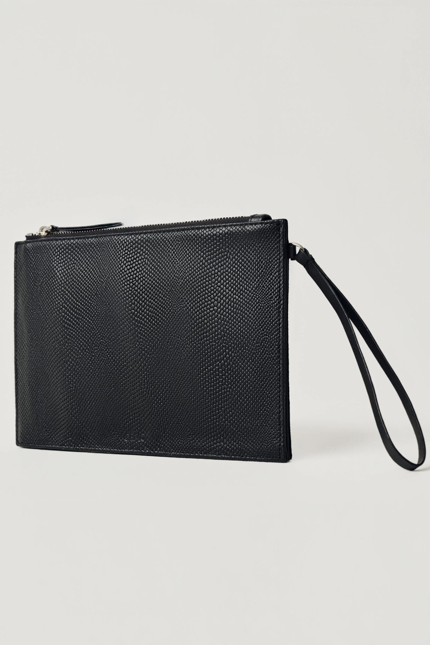 A black textured leather wristlet clutch with a top zipper and an attached wrist strap, shown on a light gray background.