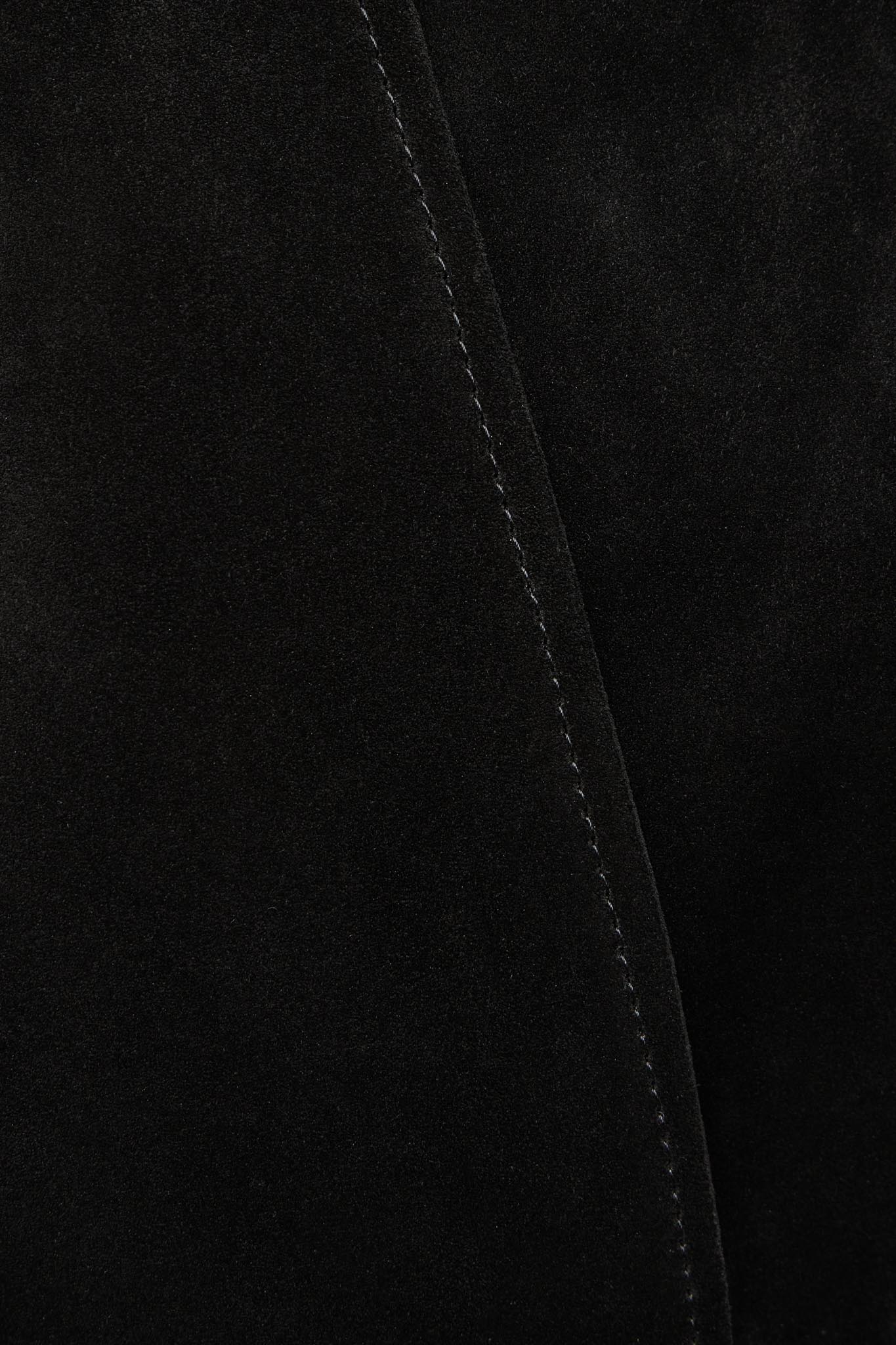 Close-up of a black suede or velvety fabric surface with a diagonal stitched seam running through the frame.