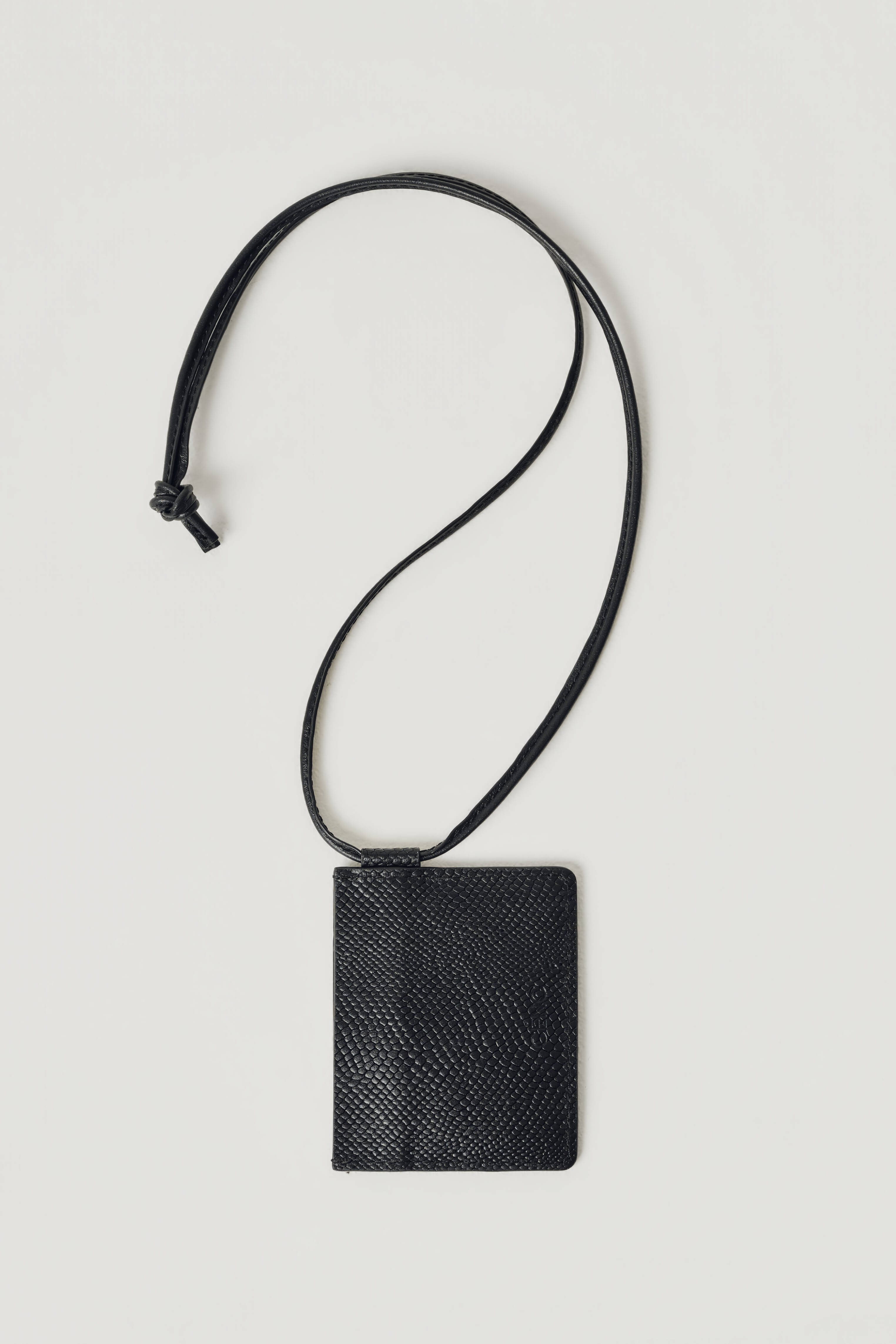 A black textured leather card holder with a matching adjustable leather neck strap, displayed flat against a light gray background.